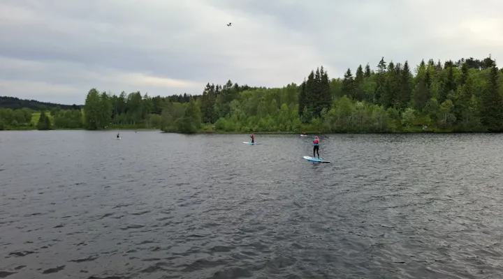 Bilde av ungdommer som padler på SUP på et vann i skogen