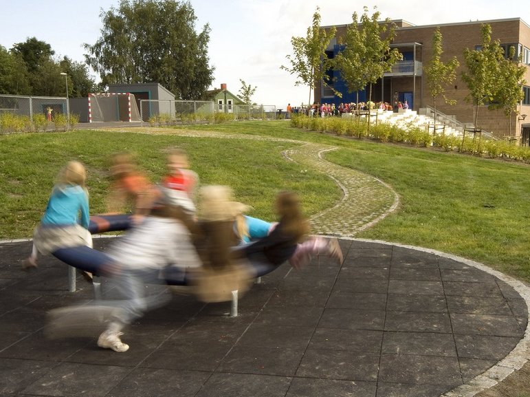 Barn på lekeapparat på fallunderlag. Lekeapparatet er tilgjengelig for alle, adkomst via steinsatt sti i plen