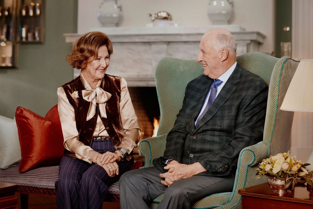 dronning Sonja og kong Harald  i en sofa på slottet i 2021.