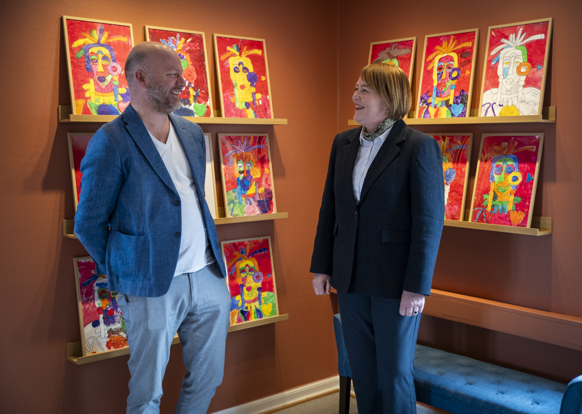 Rektor og avdelingsleder står foran en utstilling elevarbeider.