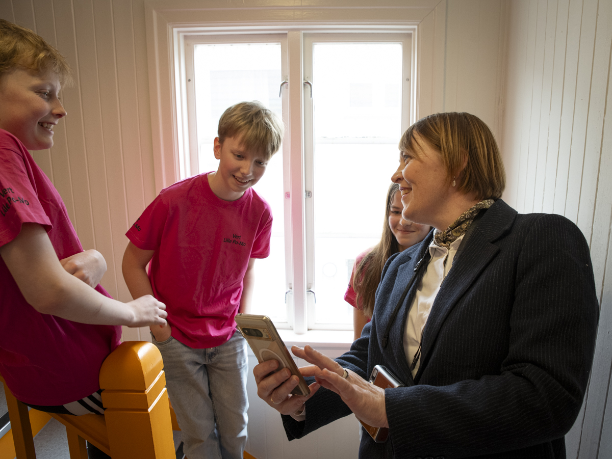 Elever og l&aelig;rer ser p&aring; bilde p&aring; mobil
