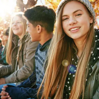 Ungdommer sitter sammen på en benk i sol