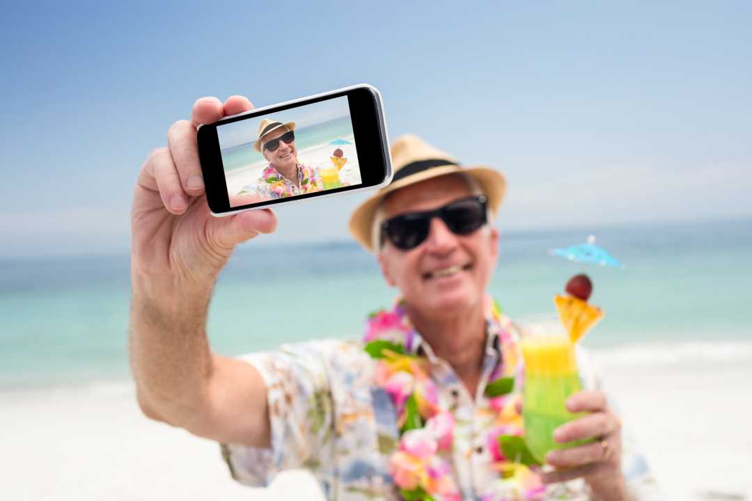 Foto av mann på stranda som tar selfie