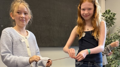 To jenter samarbeider om å lage snurrearmbånd